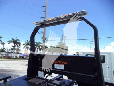 Truck bed rollover carrier with light bar on top, Jerr-Dan branding, glass window reflection, and palm trees in background.