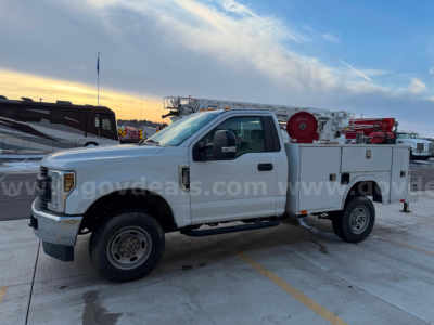 2019 Ford F250 Super Duty XL service truck in a parking lot; features utility body with hose reel and compartments.