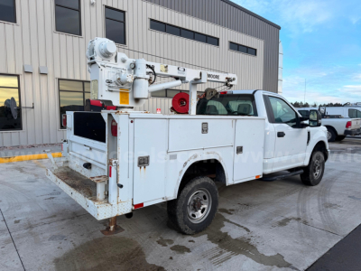 Ford F-250 Super Duty XL utility/service truck with bucket lift, white utility bed, rear mounted crane, and stabilizer legs.
