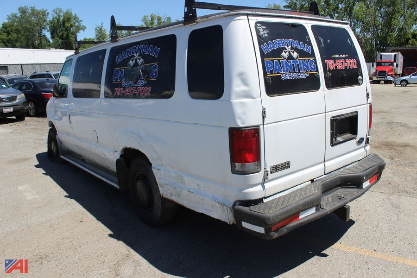 Ford E350 full-size van rear-left view showing white body, side and rear windows with advertising decals, bumper guard, and ladder rack.