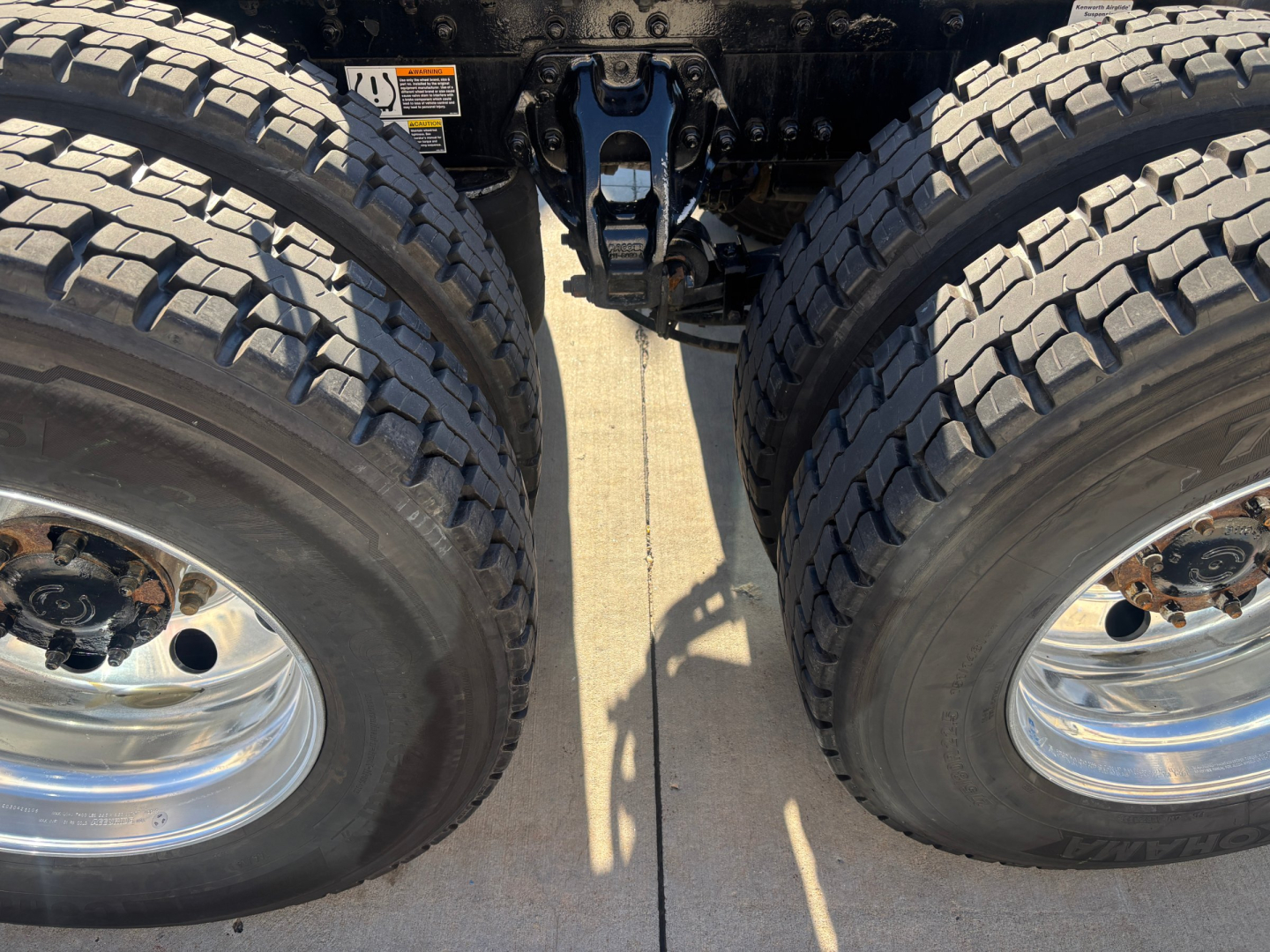 Kenworth T680 truck rear drivetrain showing dual rear wheels and suspension components.