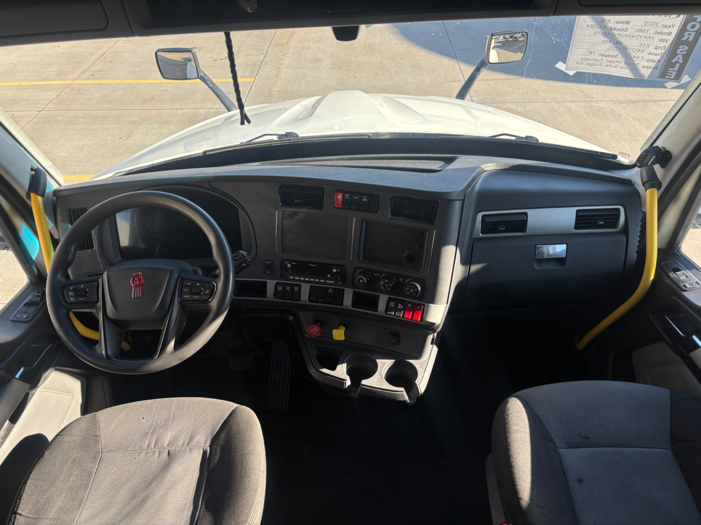 Kenworth T680 truck interior dashboard view from driver's seat showing steering wheel, instrument cluster, center controls, and wide windshield.
