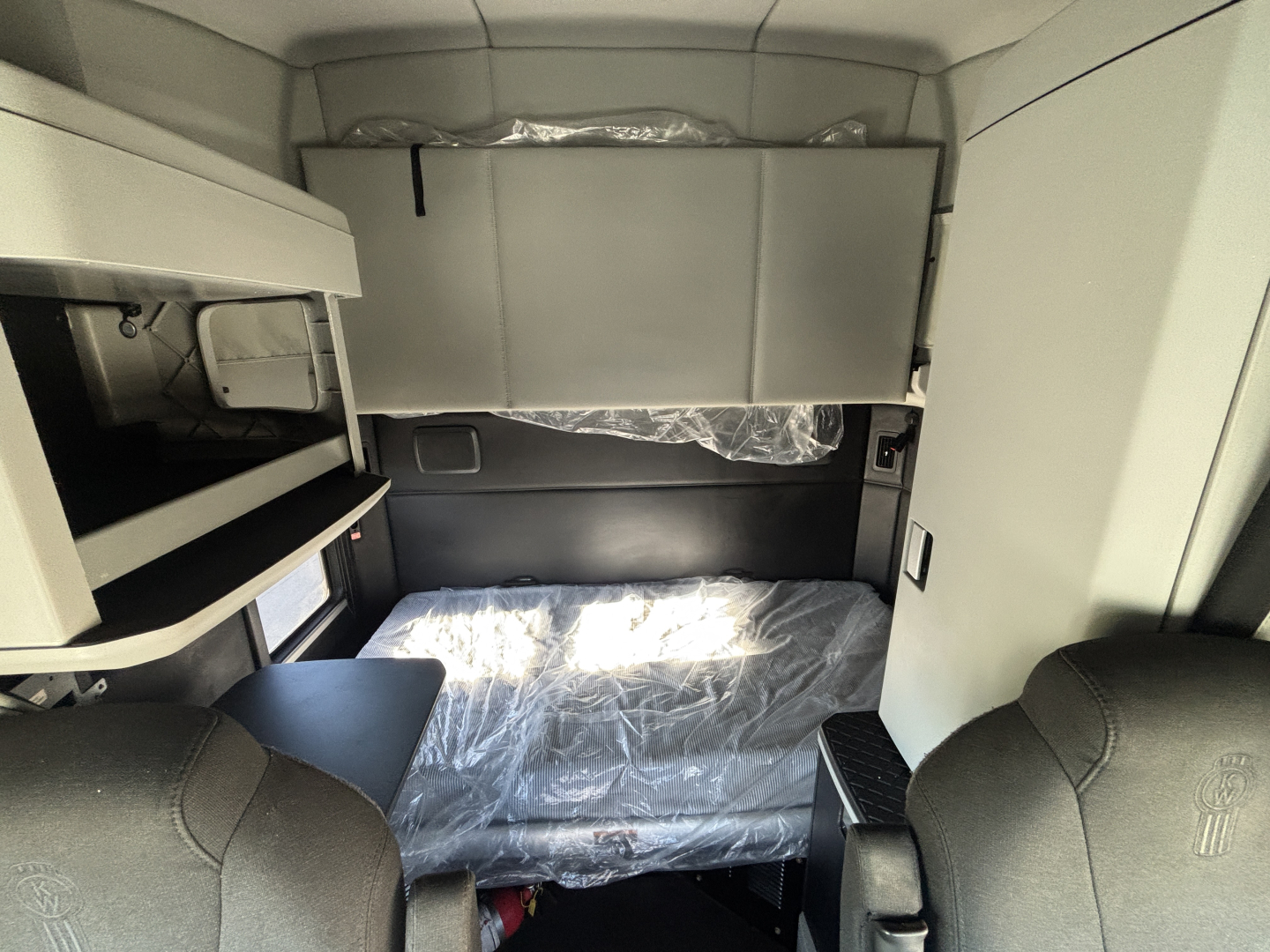 Cab interior of a Kenworth truck sleeper with bunk area and storage compartments visible.