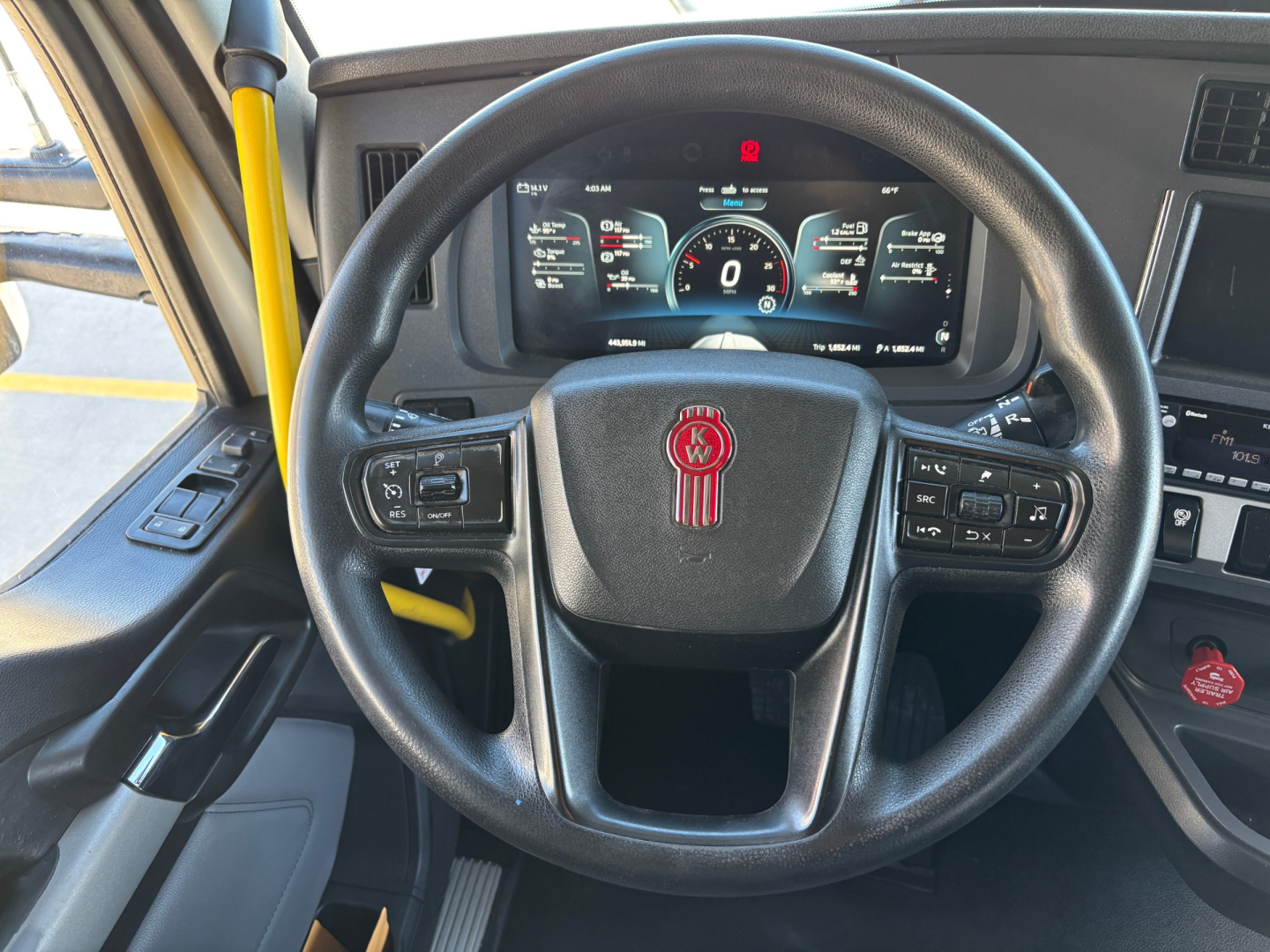 Kenworth T680 steering wheel and dashboard view with digital gauges and control stalks visible.
