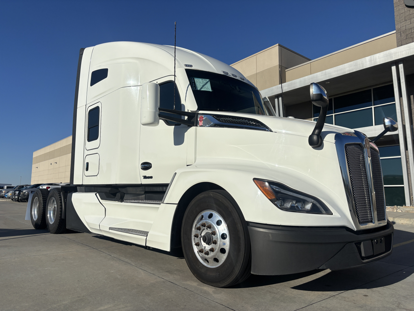 Kenworth T680 tractor in white, front-left view, with sleeper cab and dual rear axles visible.