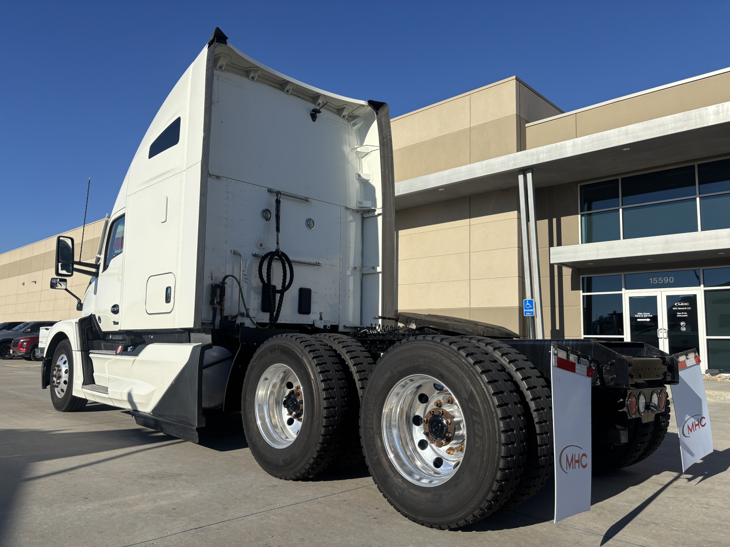 Kenworth T680 tractor rear view showing dual rear axles with chrome wheels and white cab.