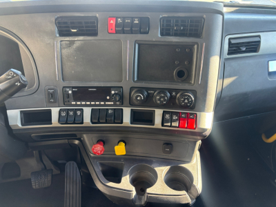 Dash and center console of a Kenworth truck cab showing climate controls, storage compartments, cup holders, and control switches.