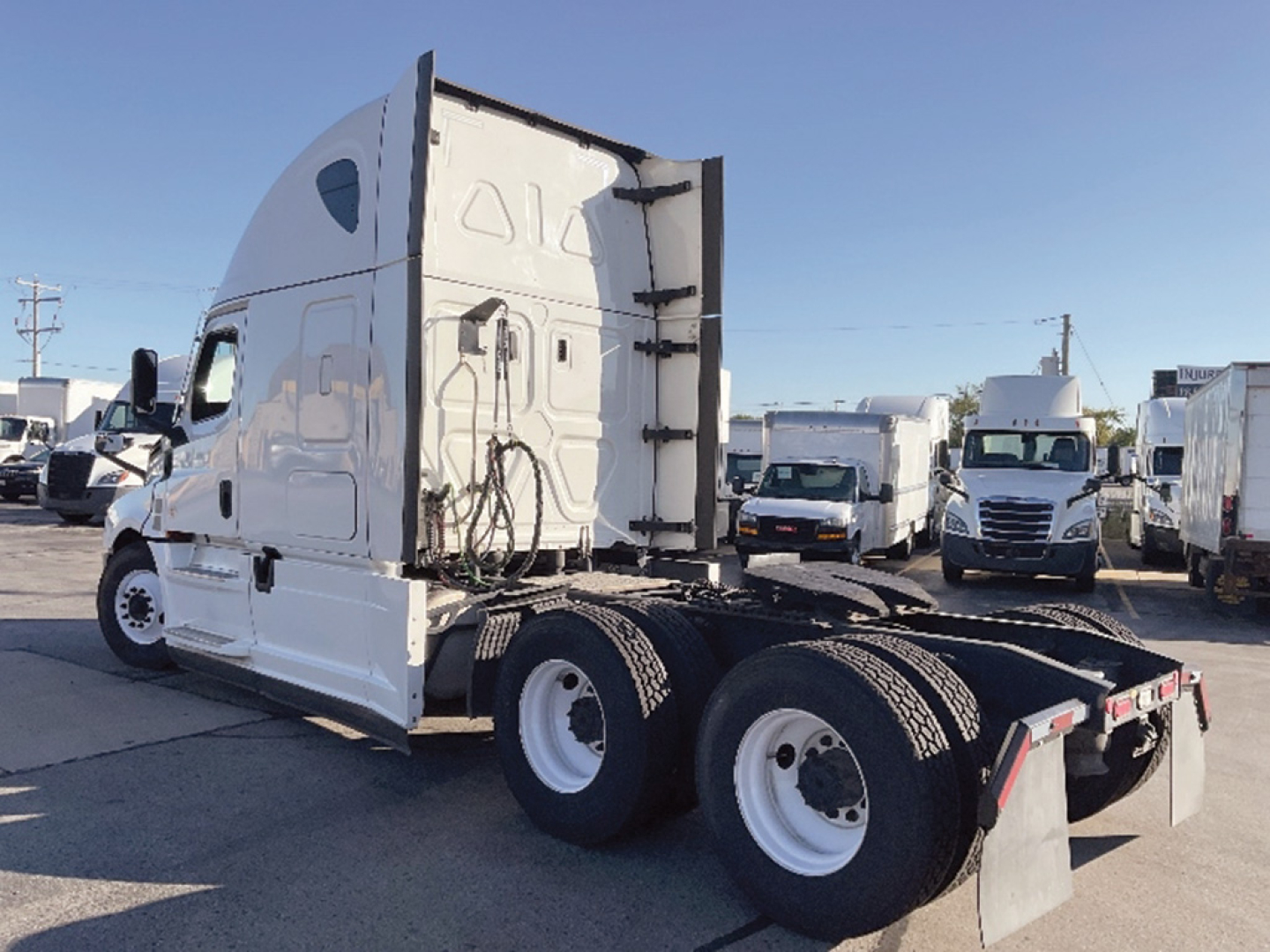 Freightliner Cascadia126 truck cab and rear view showing sleeper, dual rear axles, white exterior, cargo and trailer connection area.
