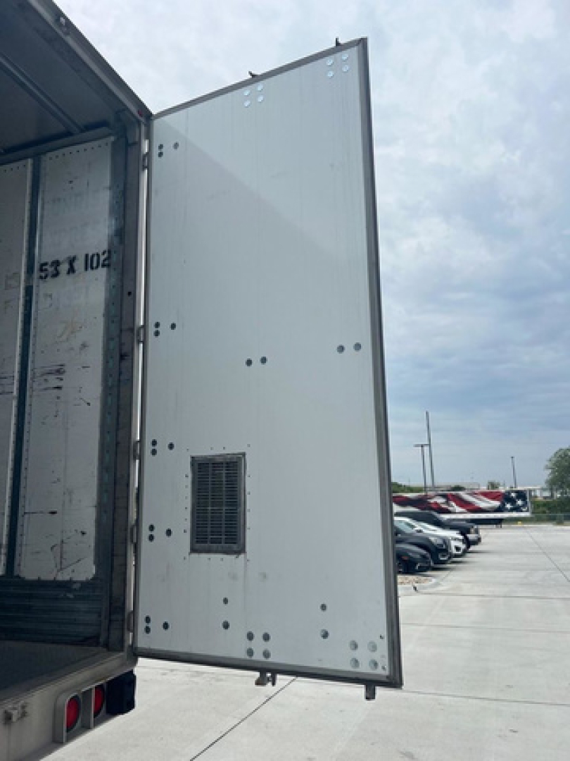 Open rear doors of a utility van trailer showing interior and the exterior door with a small vent/grille on the door pane; no legible model text visible in image.