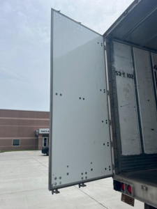 Utility van cargo area showing interior side with riveted metal panel and door hinge.
