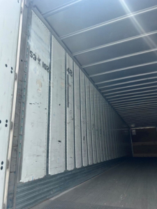 Trailer interior showing cargo walls and floor of a utility van/trailer with metal walls and ribs.