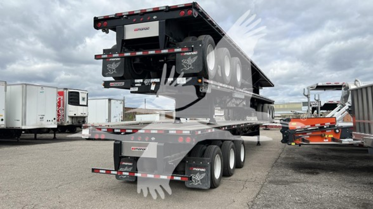 Manac extendable flatbed trailer in raised position with multiple axles and hydraulic extendable bed, visible tires and reflectors.