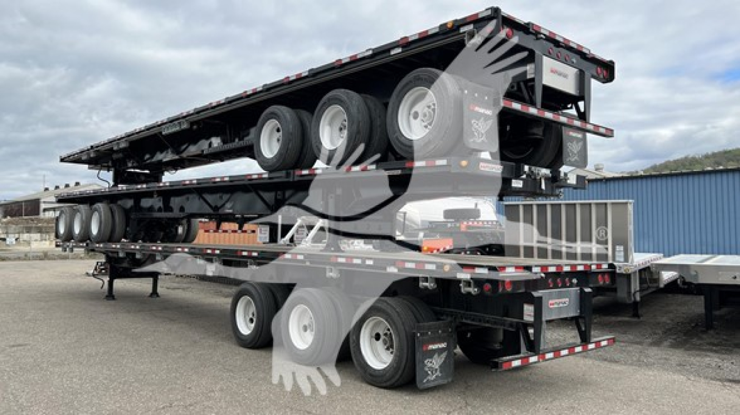 Manac extendable flatbed trailer on a multi-axle load with stacked trailers and wheels visible.