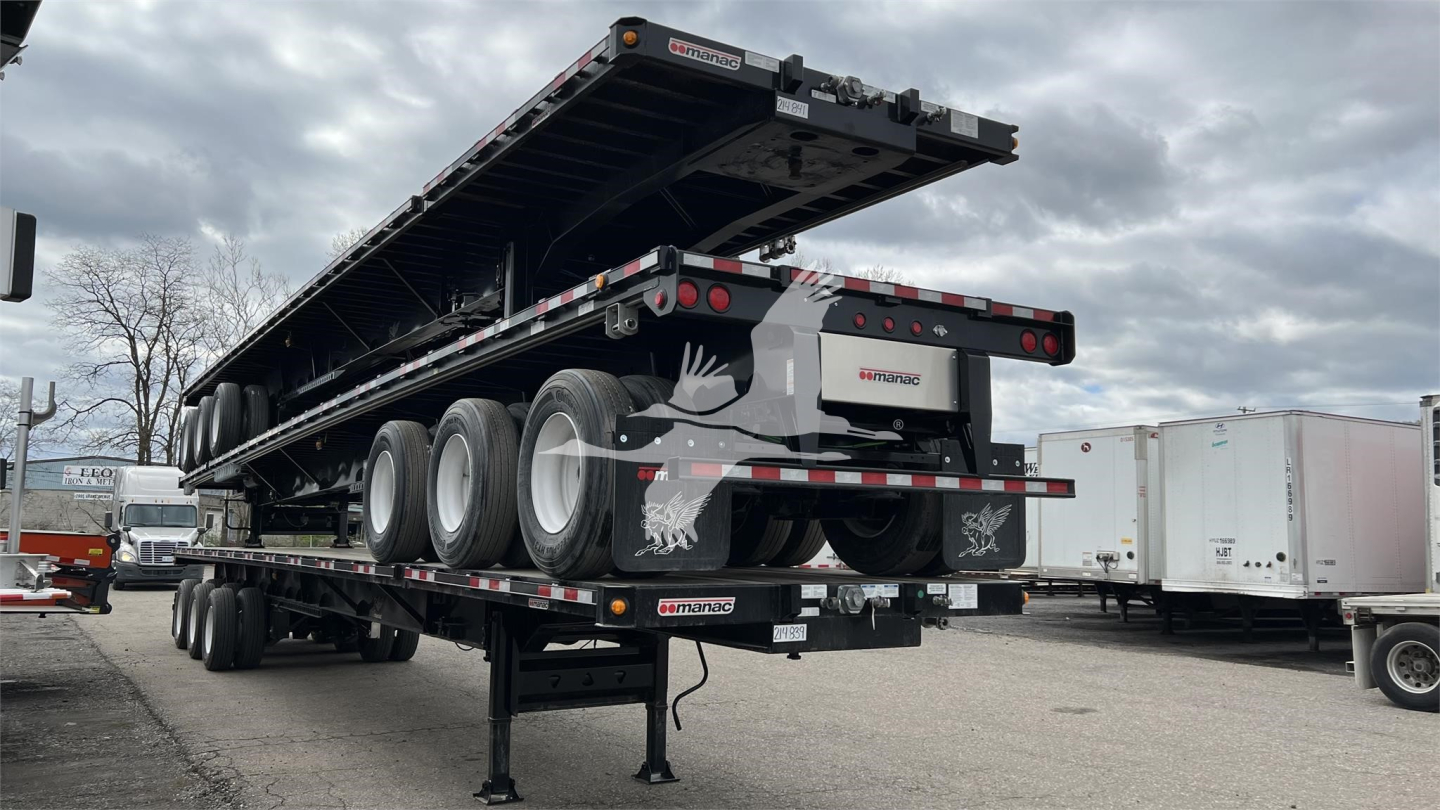 Trailing extendable flatbed trailer with multiple axles and ramps, Manac branding, rear lights, and support legs visible.