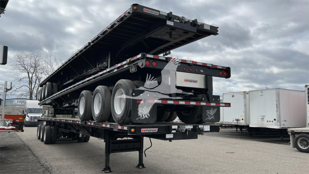 Trailing extendable flatbed trailer with multiple axles and ramps, Manac branding, rear lights, and support legs visible.