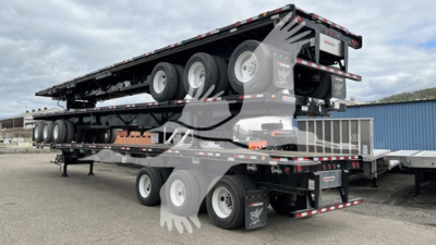Manac extendable flatbed trailer on a multi-axle load with stacked trailers and wheels visible.