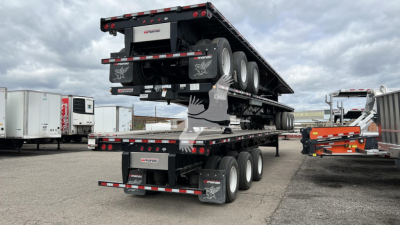 Manac extendable trailer in stacked configuration showing multiple axles and black deck with reflectors.
