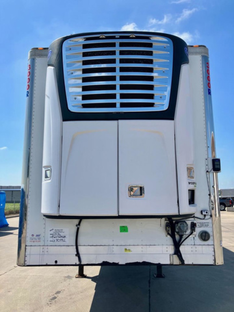 Reefer trailer front view showing large grille and lower refrigeration unit, with white cab and silver accents.