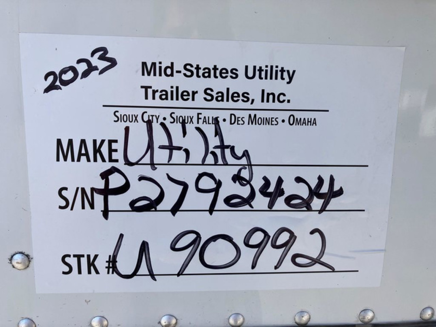 Label on a refrigerated trailer showing stock and VIN: ‘Make Utility’ with S/N P2792424 and stock number U90992, company Mid-States Utility Trailer Sales, Inc. and year 2023 handwritten.