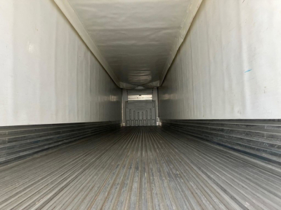 Trailer interior view of a refrigerated trailer with ribbed metal floor and white walls, looking toward the back doors.