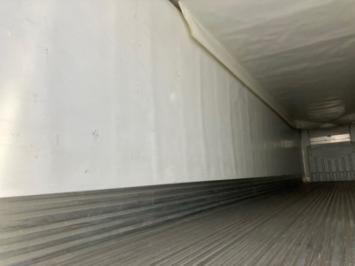 Interior of a refrigerated trailer with ribbed metal floor and smooth white sidewalls.