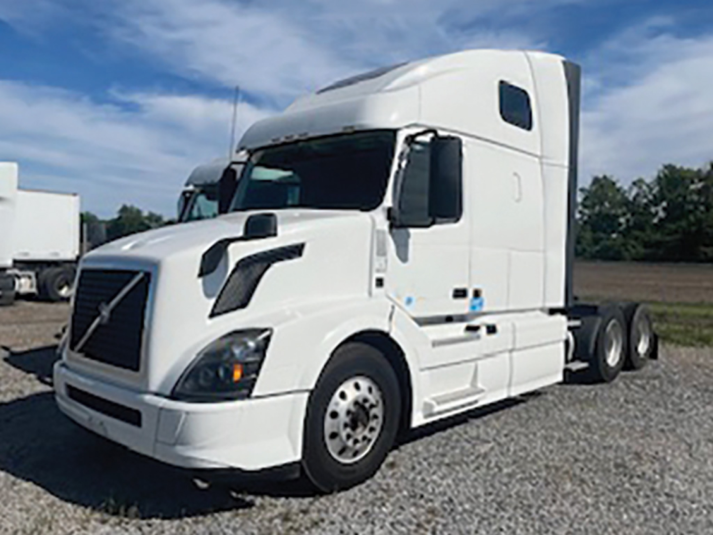 Volvo VNL 670 sleeper cab truck in white, side view showing front axle and tandem rear wheels.