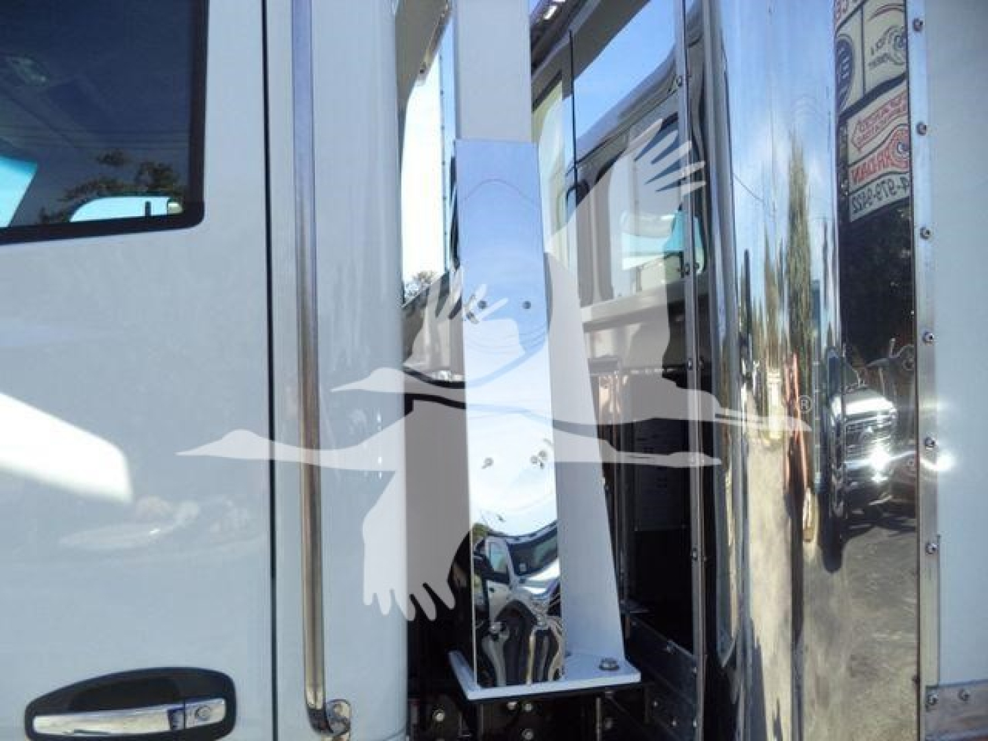 Kenworth truck cab with chrome mirror and door area visible in roll back service bay showing polished metal surfaces.
