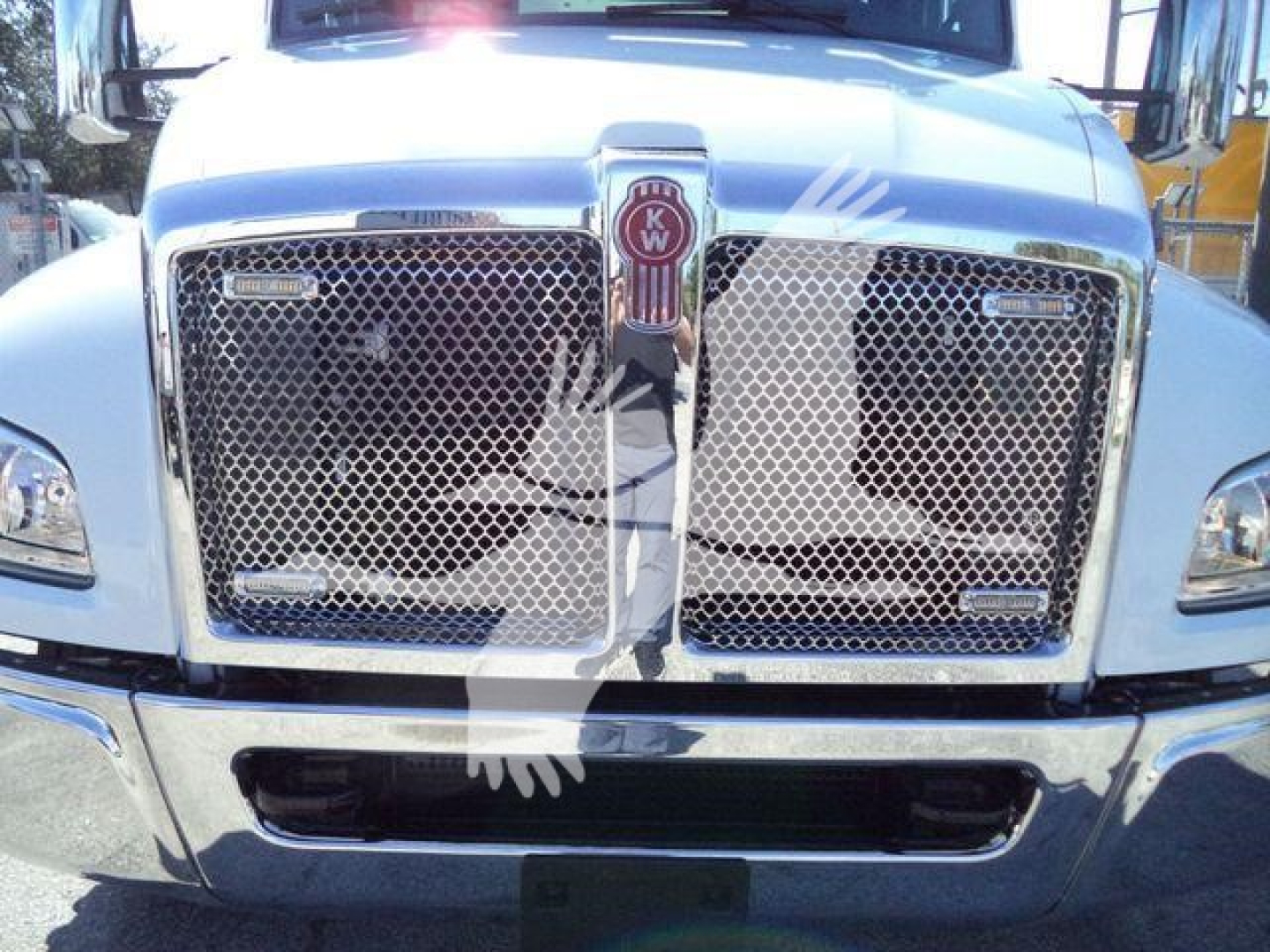 Kenworth T280 front grille and chrome bumper with KW emblem, truck head-on view in a dealership lot.