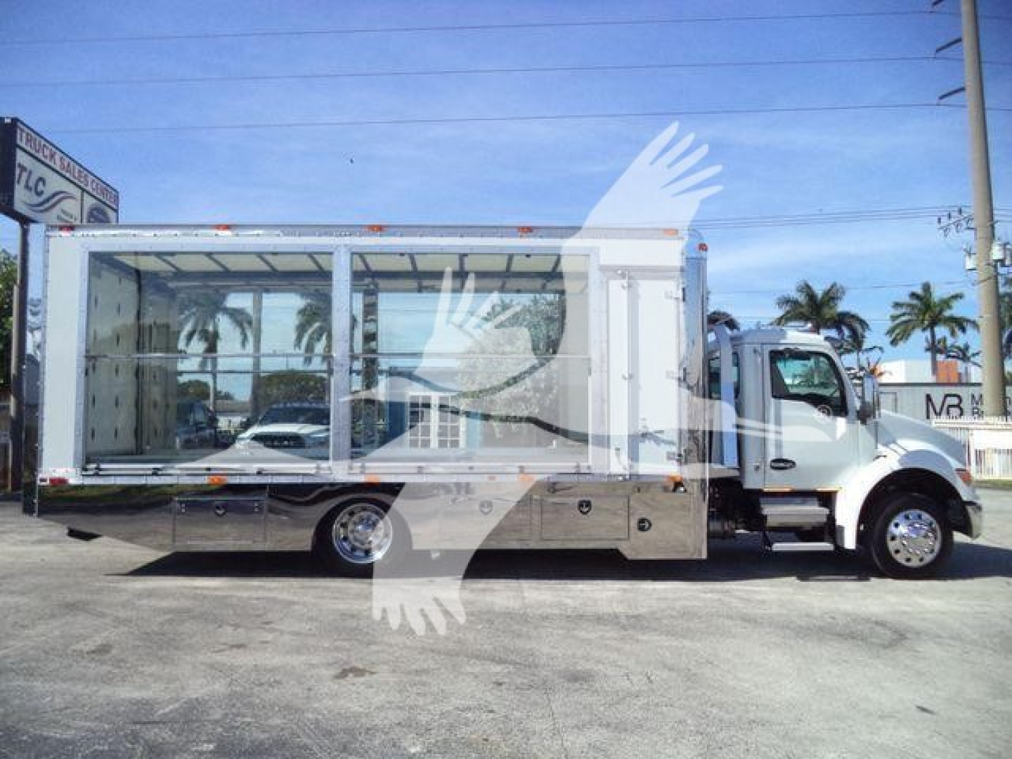 Truck side view showing a new 2025 Kenworth T280 rollback with glass cargo area and chrome underbody storage compartments.