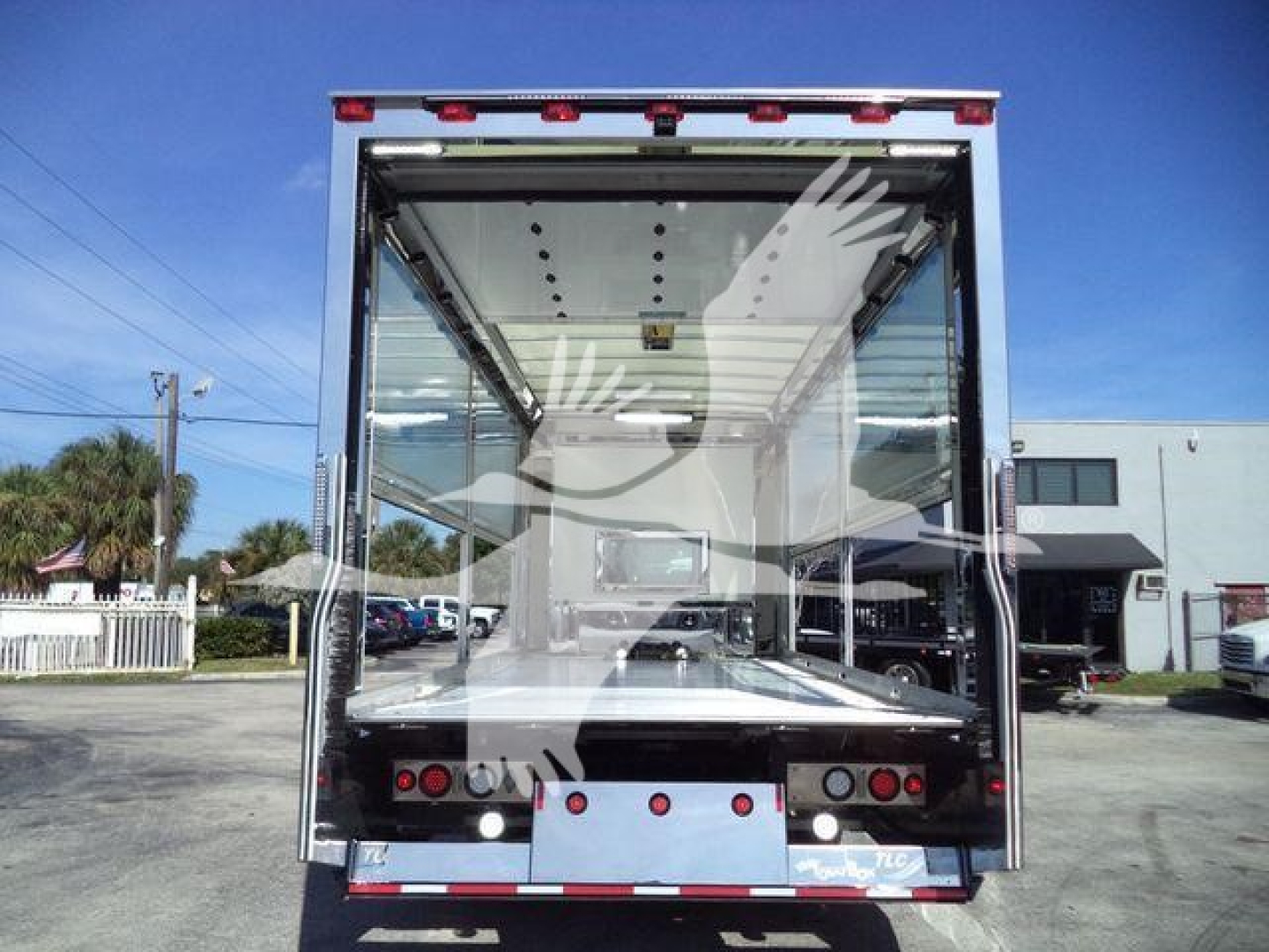 Kenworth truck rollback bed with open rear doors, showing interior cargo area and rear lights; no legible labels visible in image.
