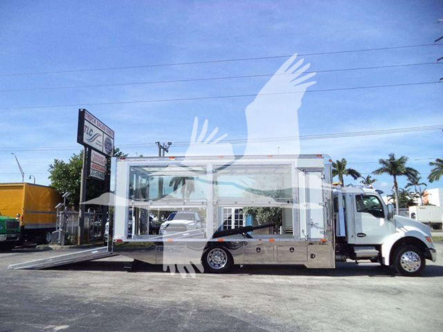 Kenworth T280 rollback truck in white with loading ramp extended showing side compartments and chrome accents.