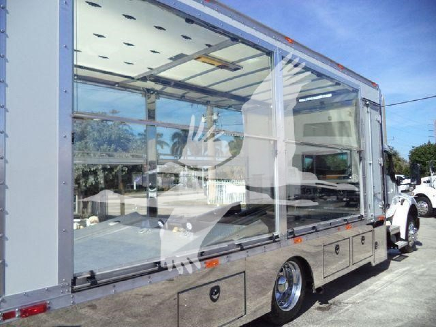 Kenworth T280 rollback truck with transparent side enclosure showing interior workspace and windows.
