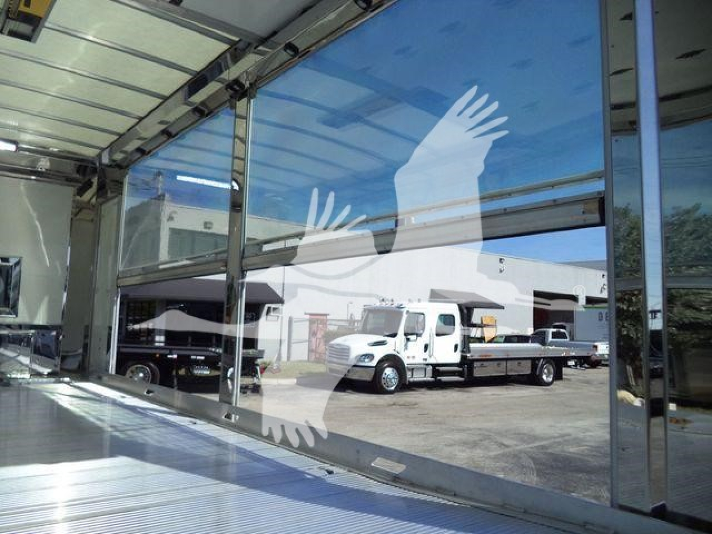 Kenworth T280 rollback truck inside a service bay with bay door reflecting exterior trucks.