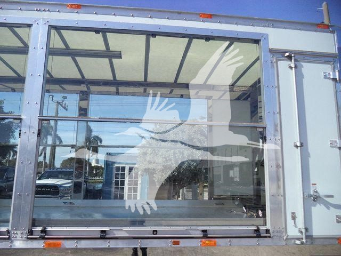 Kenworth T280 rollback truck cab rear window with metal frame and glass panels, reflection of surroundings visible.