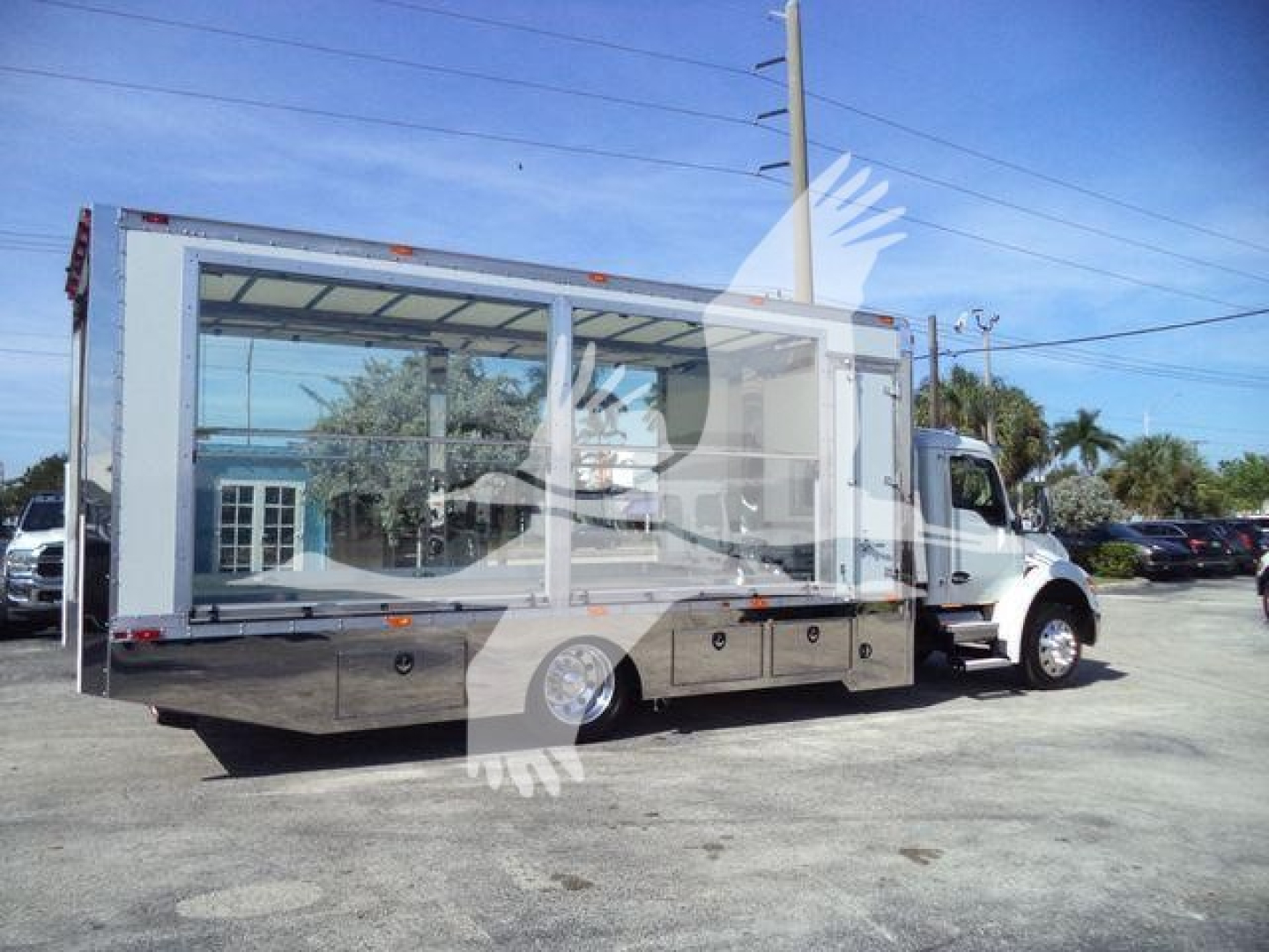 Kenworth T280 rollback truck with large glass display area on side, chrome lower body panels, and multiple storage compartments along the chassis.