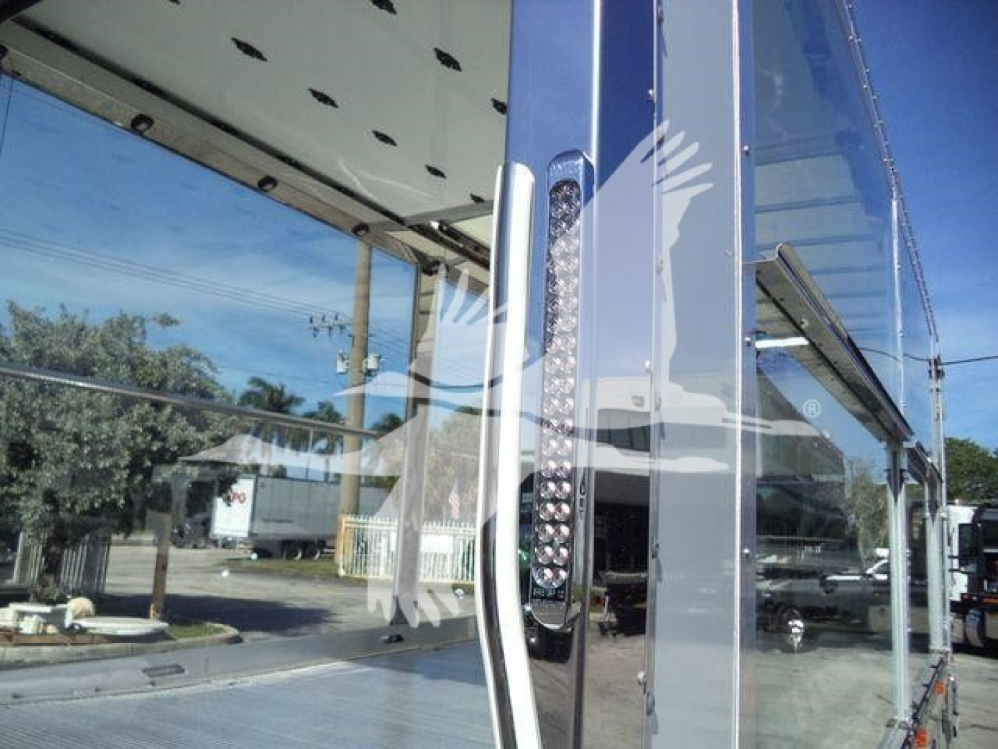 Kenworth T280 rollback truck front cab and side mirror visible with reflection in glass and metal components.