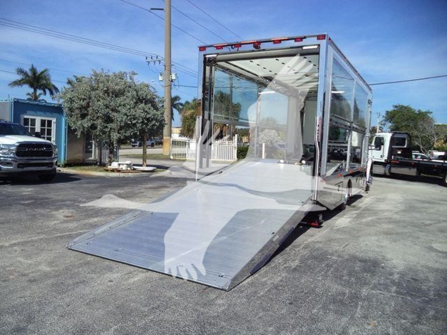 Kenworth T280 service/rollback truck with a large aluminum cargo ramp extending to the ground, glass cabin, and reflective chrome frame.