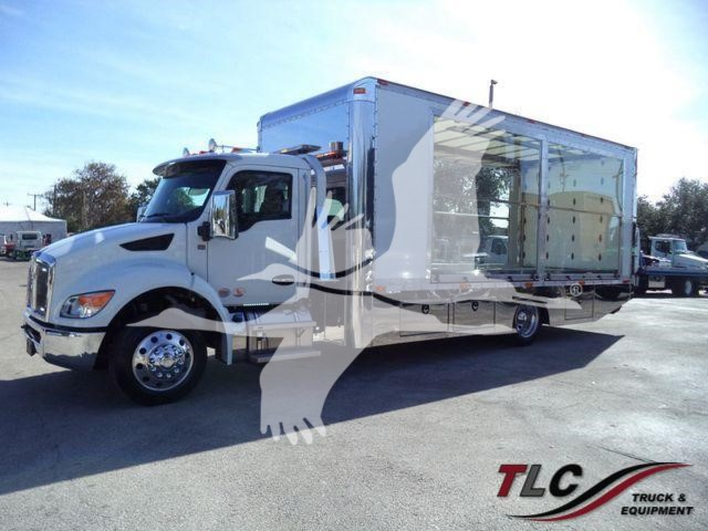 Kenworth T280 rollback truck with large aluminum cargo box, front cab, and side bay windows visible in parking lot.