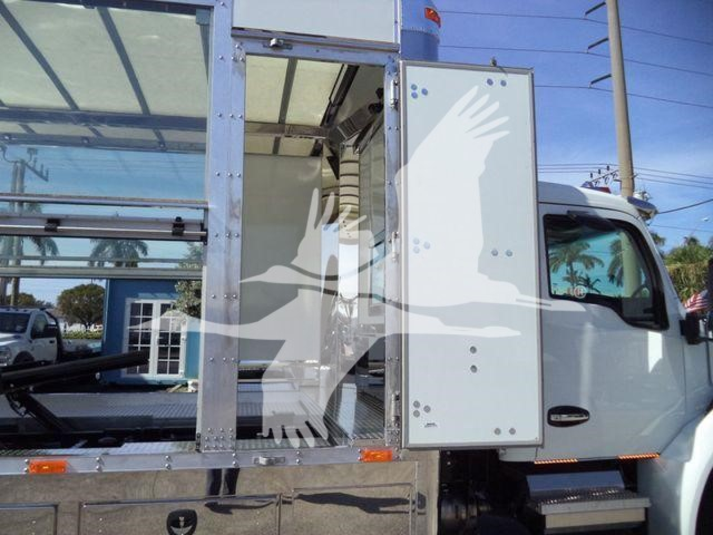 Truck cab interior showing storage compartments with metal frames and a doorway; side door open with light gray panels.