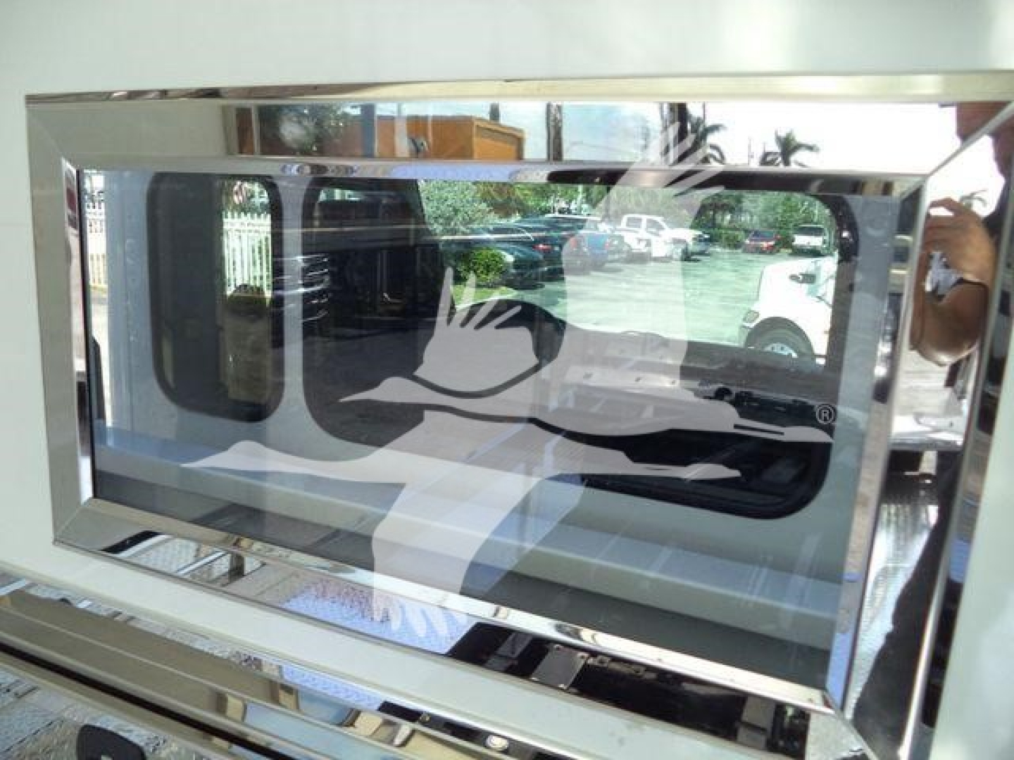 Truck equipment image showing a large chrome-framed window or display with reflective surface and a white graphic overlay.