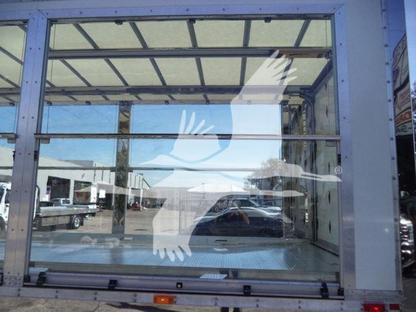 Truck cab window showing clear interior with metal framing and reflection of vehicles; no visible text or labels.