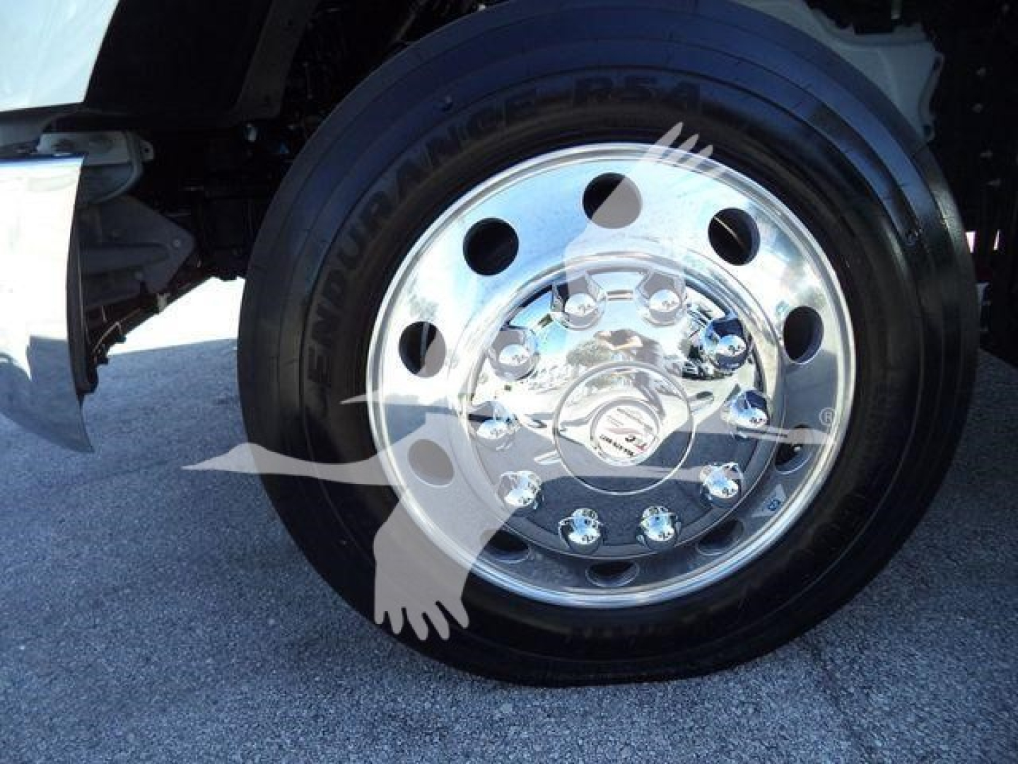 Wheel close-up on Kenworth T280 rollout truck showing polished chrome hubcap and tire tread.