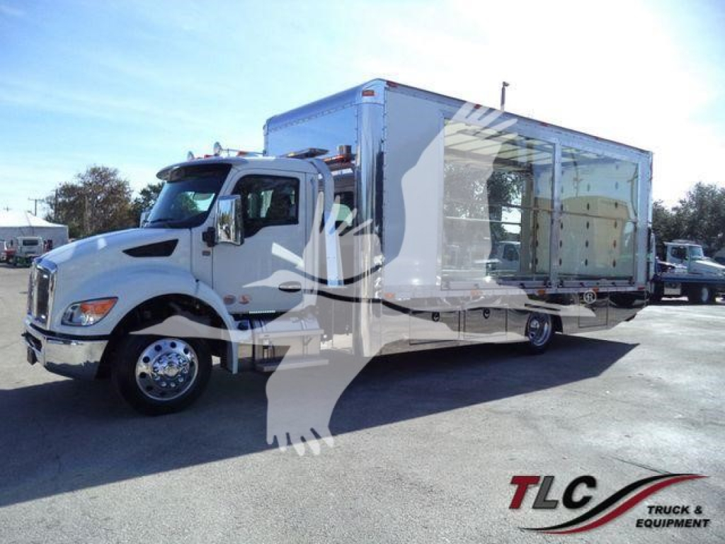 Kenworth T280 rollback truck with large aluminum cargo box, front cab, and side bay windows visible in parking lot.