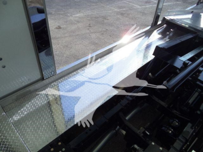 Truck wheel well area with diamond plate metal surface and hydraulic components visible in a rollback truck bed.