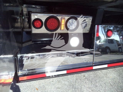 Rear of a Kenworth rollback truck showing taillights, reflectors, and a reflective decal with a bird graphic.
