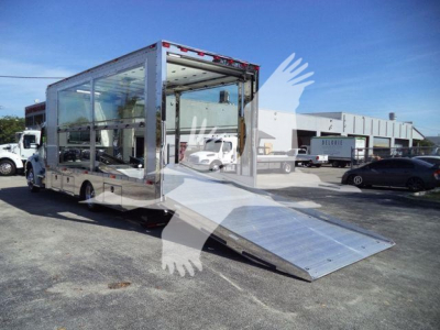 Kenworth T280 rollback truck with aluminum ramp extended, side and rear glass panels visible, in a lot with other trucks.