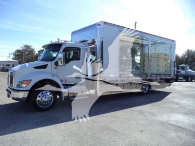 Truck with a large box body on a rollback trailer. Front cab shows side mirror and dual headlights; large wheel wells; text not clearly legible on decals.