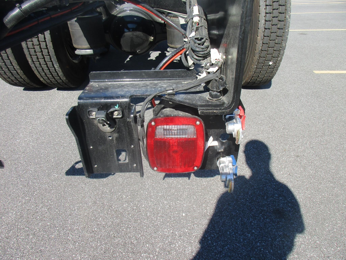 Rear view showing tail light assembly and bumper area of a Freightliner M2 106 Plus cab and chassis, with wiring and mounting brackets visible.