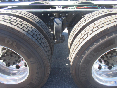 Truck chassis showing dual rear tires and rear suspension coupling with visible bolts and frame crossmember.