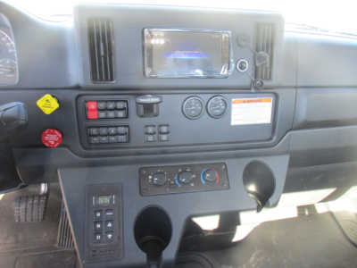 Dashboard view of a Freightliner M2 106 Plus cab and chassis showing center touchscreen display, climate controls, switches, and gauges.